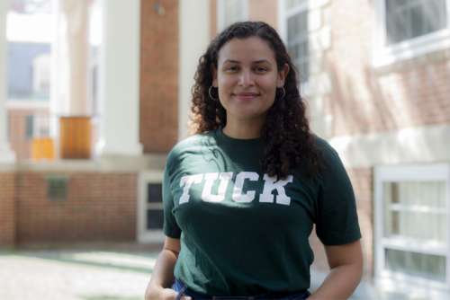 Tuck student standing in front of Tuck Hall wearing a tshirt that says Tuck
